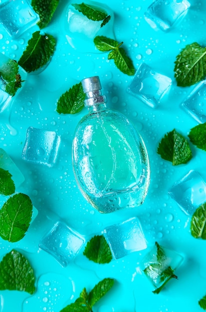 Perfume on a blue background with ice cubes and mint Selective focus