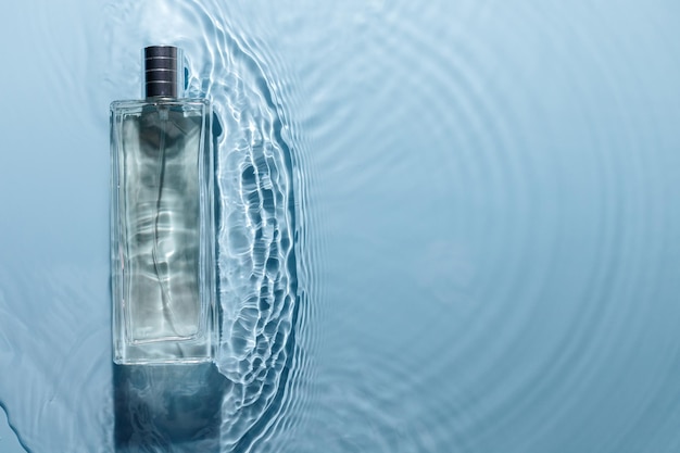 Perfume bottle on blue water wavy background Fresh sea fragrance concept Pure