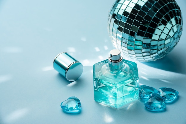 Perfume bottle, disco ball and crystal hearts on a blue wall