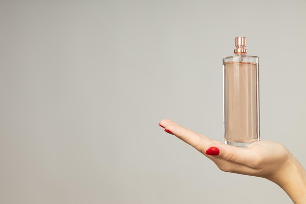 Foto bottiglia di profumo in mano femminile su sfondo bianco spazio per il testo