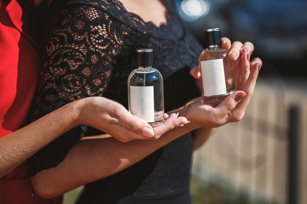 Perfume bottle of a female hand. Young stylish woman holding a bottle of perfume. Fashionable perfume in the hands of women. Girl spraying perfume. Beautiful female hands. Perfumes for women