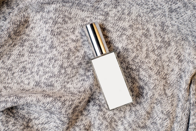 Perfume bottle on gray crumpled fabric. Beauty, skin care.