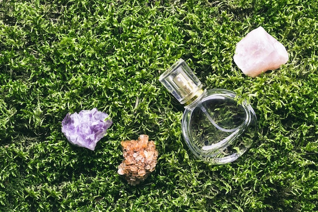 Perfume bottle and minerals stones on beautiful moss background. Nature fragrance beauty concept.