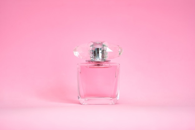 Perfume bottle sprayed on pink pastel background