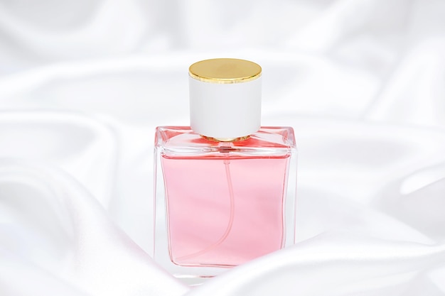 Perfume bottle on a white silk background. Fragrance cosmetic product.