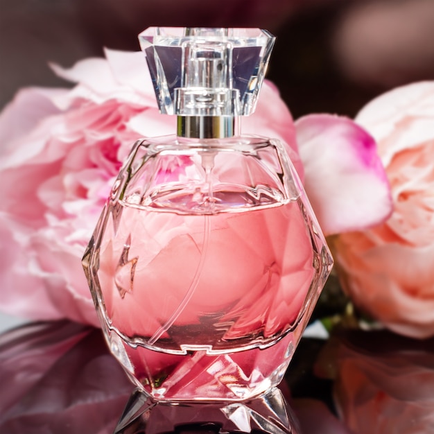 Perfume bottle with flowers on dark surface