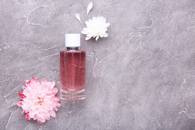 Perfume bottle with flowers on grey concrete background