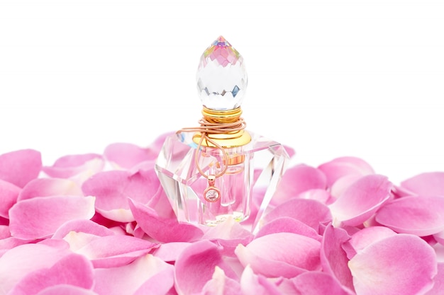 Foto bottiglia di profumo con collana tra petali di fiori. profumeria, cosmetici, collezione di fragranze