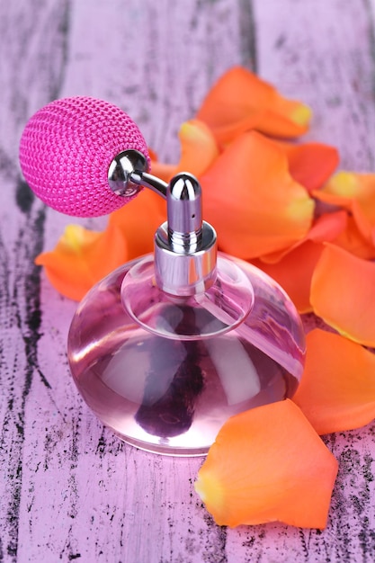 Perfume bottle with petals on table closeup