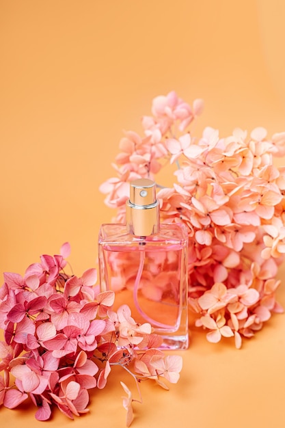 Perfume Bottle with pink flowers on pastel background. Beauty concept