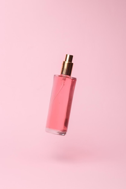 perfume bottle with pink liquid flying in antigravity on pink background with shadow levitation object in the air beauty and fashion concept creative minimalist layout