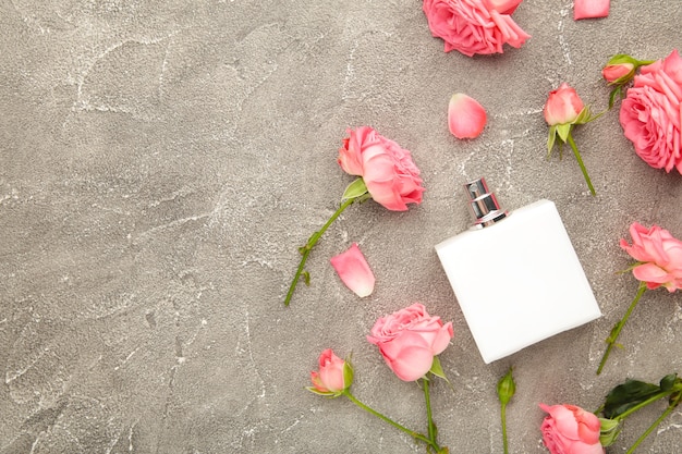 Perfume bottle with pink roses on grey