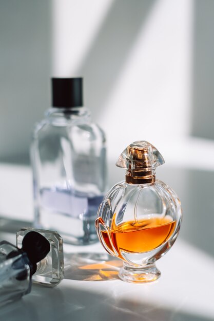 Perfume bottles on white background with sunlight shadow.