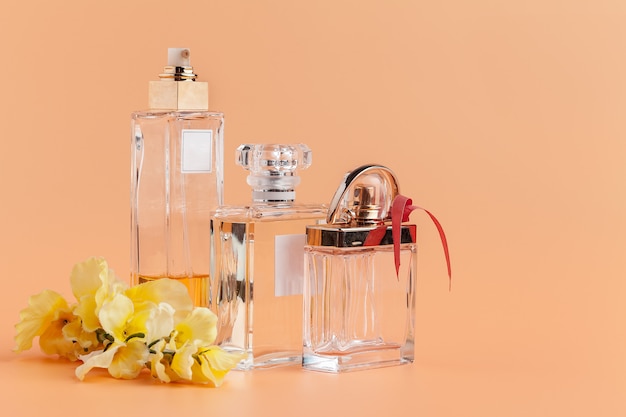 Perfume bottles with flowers petals on beige 