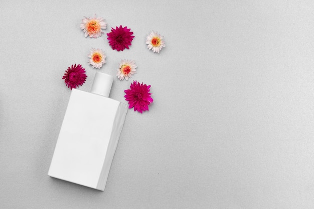 Perfume spray bottle and little flowers on gray background close up