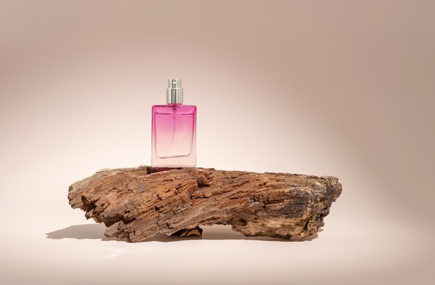 Perfume in a spray bottle and tree bark on a beige background