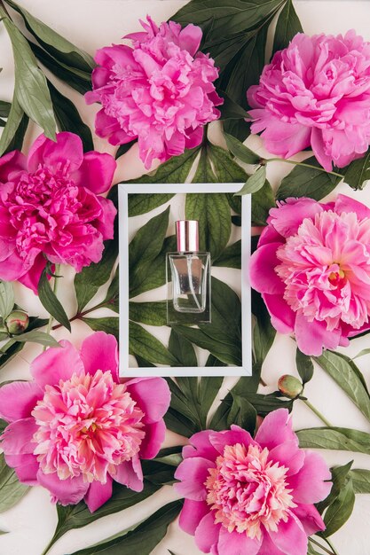 Perfume in a white frame with peonies on a pastel background Mock up Trendy fashion concept