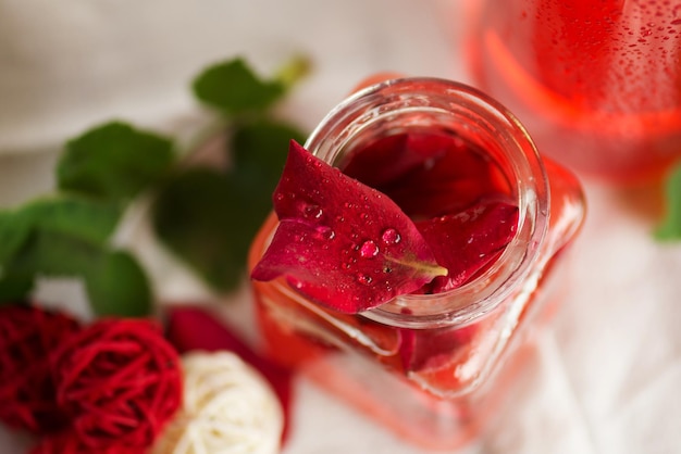 Perfumed rose water Spa set with rose petals oil Pink rose flower and glass of rose water Fresh organic rose water