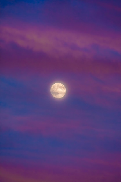 Луна в перигее (Суперлуна) в окружении пурпурных облаков на закате с темно-синим небом, ближайшая точка нашего спутника к планете Земля.