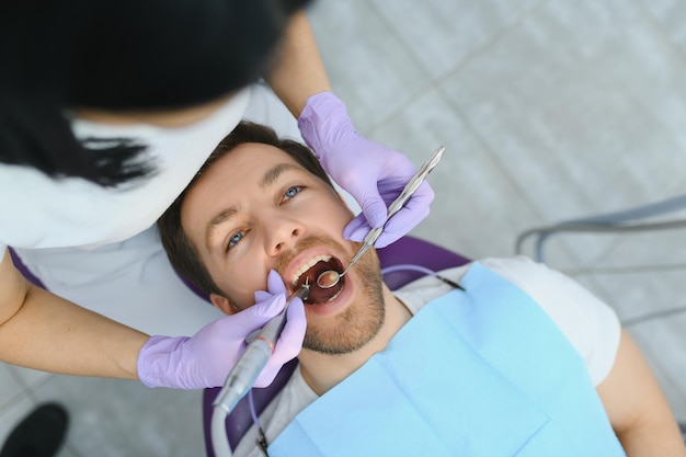 Periodontal Services Closeup Shot Of Smiling Man Getting Treatment In Stomatologic Clinic Dentist Doctor In Gloves Using Sterile Dental Tools For Examining Teeth Of Male Patient