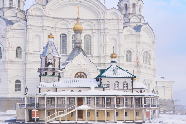 Perm krai, rusland - 21 december 2020: mock-up van een oude kerk op de achtergrond van een echte tempel van het belogorsky-klooster op een mistige winterdag