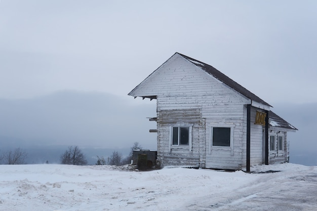 Фото Пермский край, россия - 21 декабря 2020 года: старое деревянное здание транспортного кафе на вершине горы в снежном зимнем пейзаже