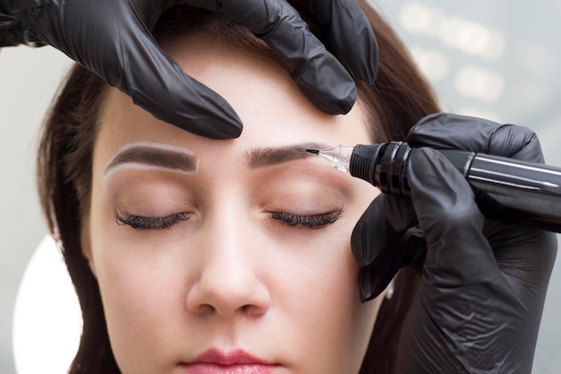 Permanent eyebrow makeup. The girl in the salon is doing permanent makeup. Tattooing. A girl in a beauty salon.