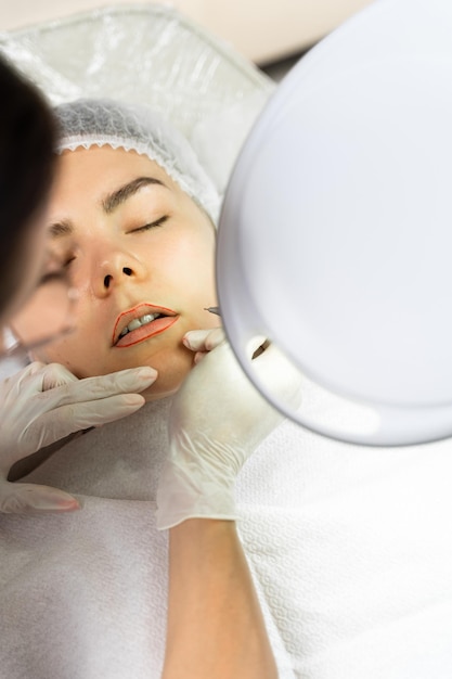 Permanent makeup artist and her client during lip blushing procedure