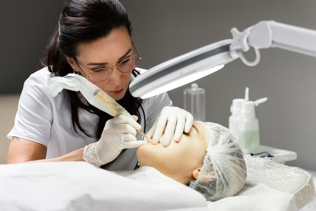 Permanent makeup artist and her client during lip blushing procedure