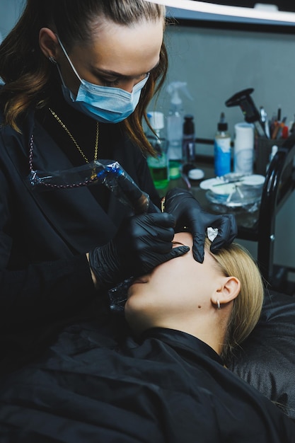 Permanent makeup Beauty procedures The master applies a tattoo on the eyebrows Professional facial microblading Women's cosmetology device