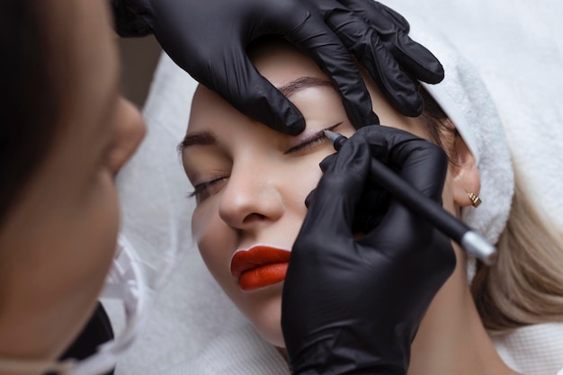 Permanent makeup Cosmetologist tattoo artist applies a contour to the client39s eyelid for subsequent application of eye tattooing