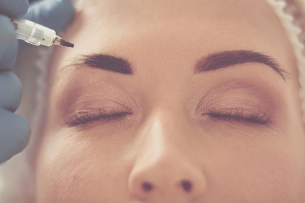 Permanent makeup for eyebrows Closeup of beautiful woman with thick brows in beauty salon