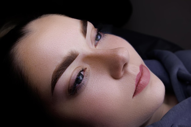 Permanent makeup of the eyebrows closeup of the model's face the master holds the eyebrows with his hands