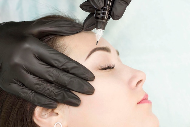 Permanent makeup The master applies permanent makeup to the eyebrows Microblading