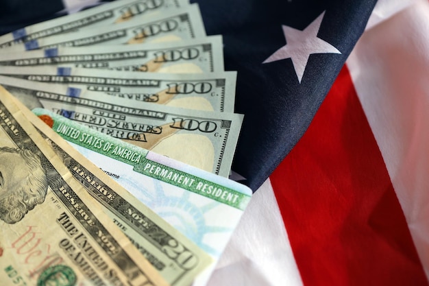 Permanent resident united states of america green card and dollar bills on folded us flag