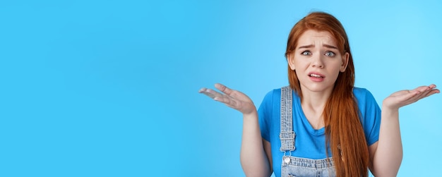 Foto perplex, ongemakkelijk, verbijsterd, bezorgde roodharige vrouw die haar schouders ophaalt, geen idee heeft dat zenuwachtig fronsen niet ongedaan kan worden gemaakt