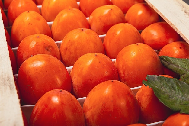 Persimmon box close-up rijpe dadelpruimen liggen in even rijen in een doos te koop