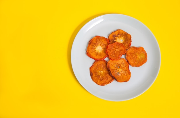 Persimmon chips lie on a porcelain plate