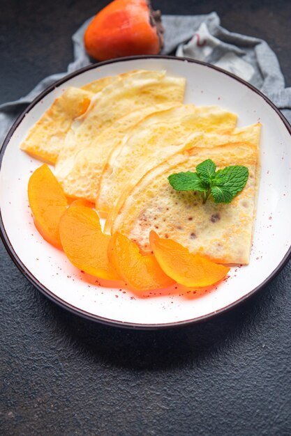 Persimmon dunne pannenkoeken fruit crêpe ontbijt zoet dessert gezonde maaltijd eten snack op tafel