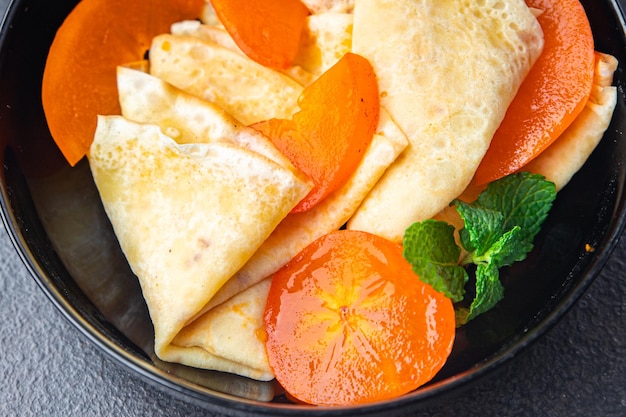 Persimmon dunne pannenkoeken fruit crêpe ontbijt zoet dessert gezonde maaltijd eten snack op tafel