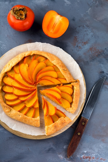 Persimmon galette, pie, tart on a gray stone background. Top view. Selective focus.