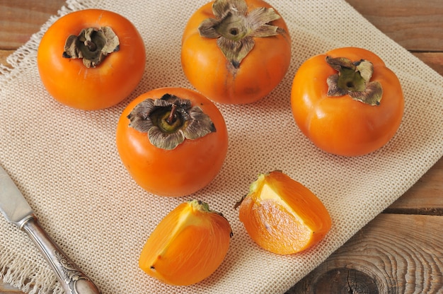 Persimmon whole and cut into pieces on canvas