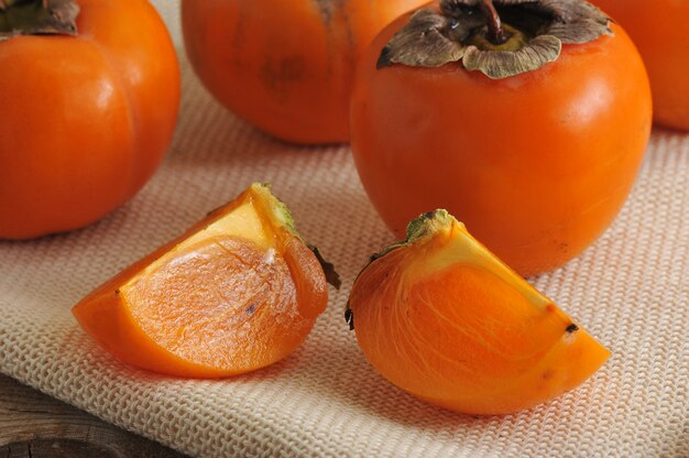 Persimmon whole and cut into pieces on canvas