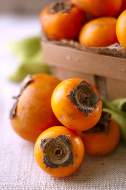 Persimmons in a basket and scattered on the table rustic style