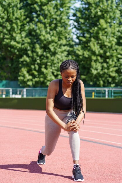 Photo persistent black woman with long braids tries hard to pump gluteal muscles taking care of fit body