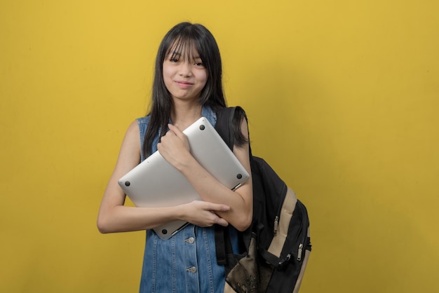 写真 バック グラウンドでコンピューターのラップトップを保持しているジーンズを身に着けている人アジアの十代の少女教育学校のコンセプトに戻って学ぶコピー スペース