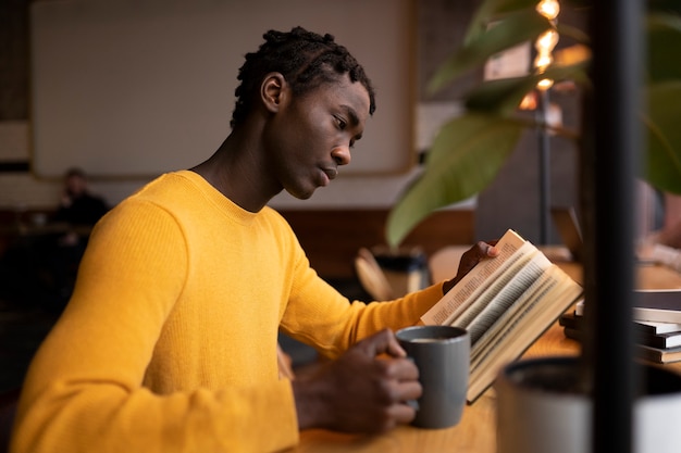 Foto persona in un caffè che legge un libro