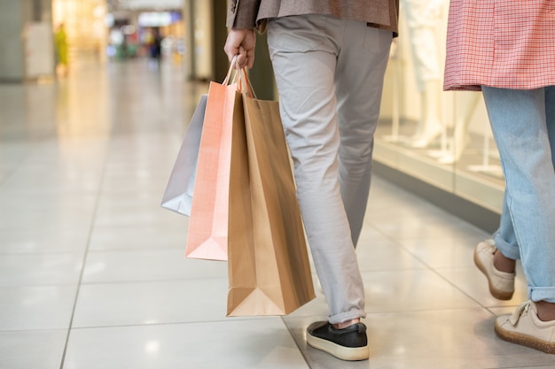 Una persona che trasporta una borsa della spesa mentre si muove all'interno del centro commerciale