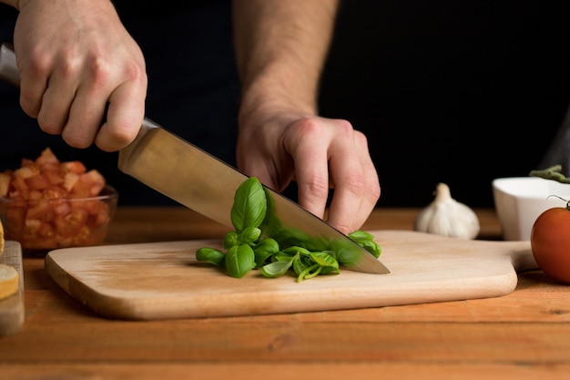Person chopped fresh basil Process of preparing italian snack bruschetta wooden table