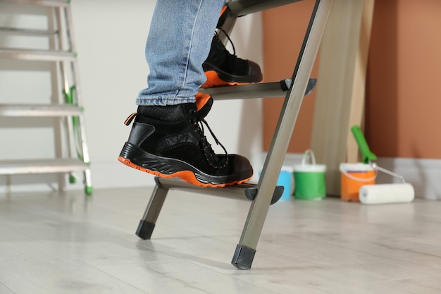 Person climbing ladder indoors closeup on feet